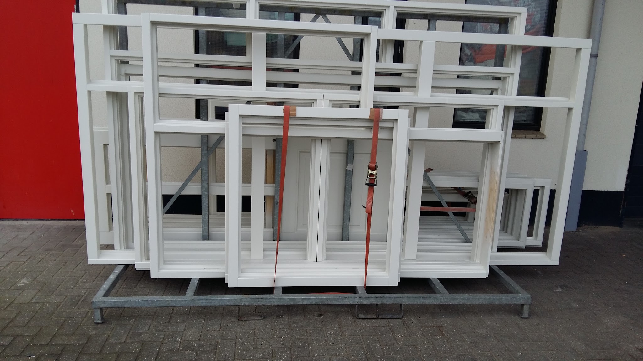 Nieuwe witte houten kozijnen op een transportbok, klaar voor plaatsing